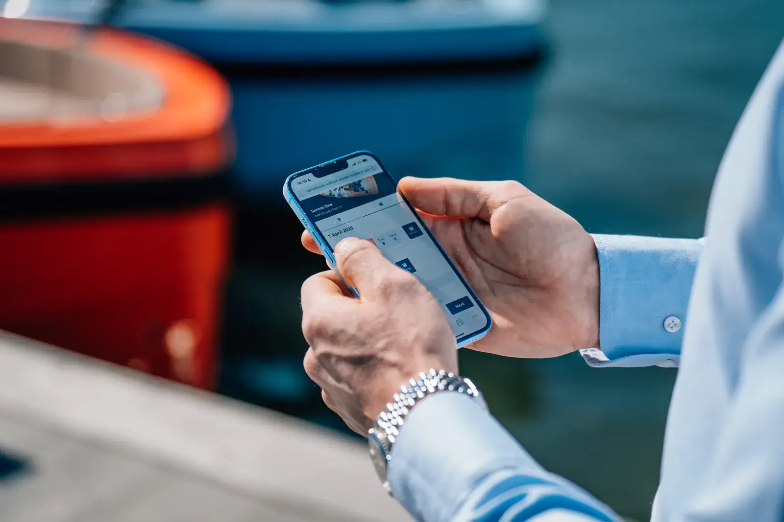 Hands holding a phone with a booking open, at the edge of a dock