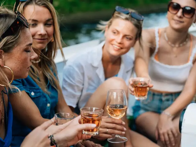 A group of friends toasting with drinks aboard an open boat