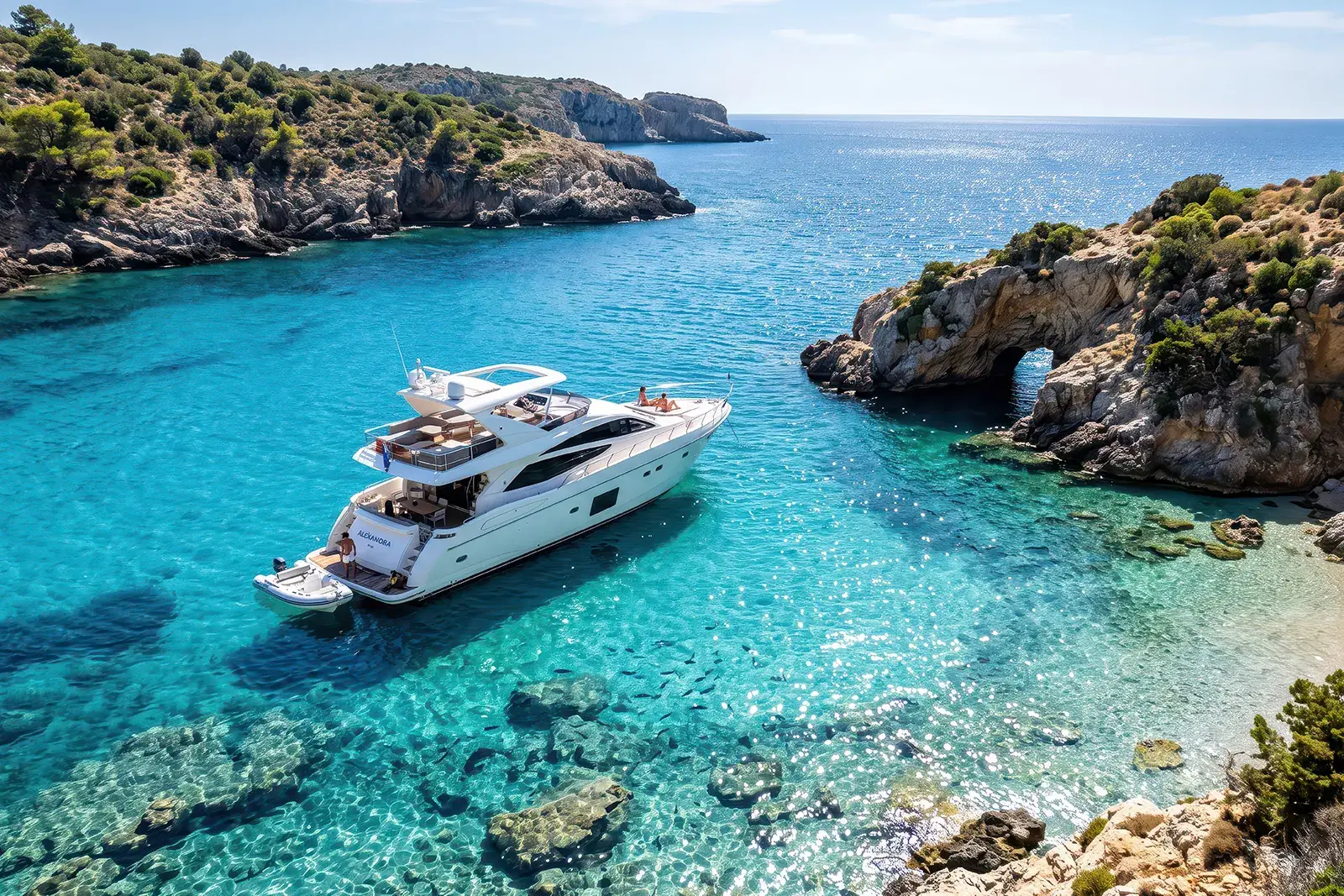 A charter yacht at anchor in a quiet cove with clear blue water
