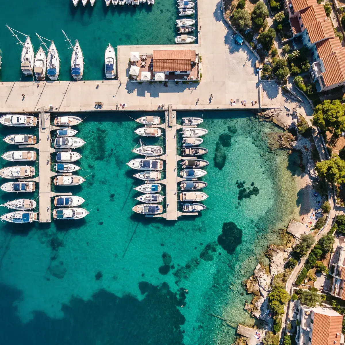 Een moderne jachthaven met dagboten en jachten in turquoise water, van bovenaf