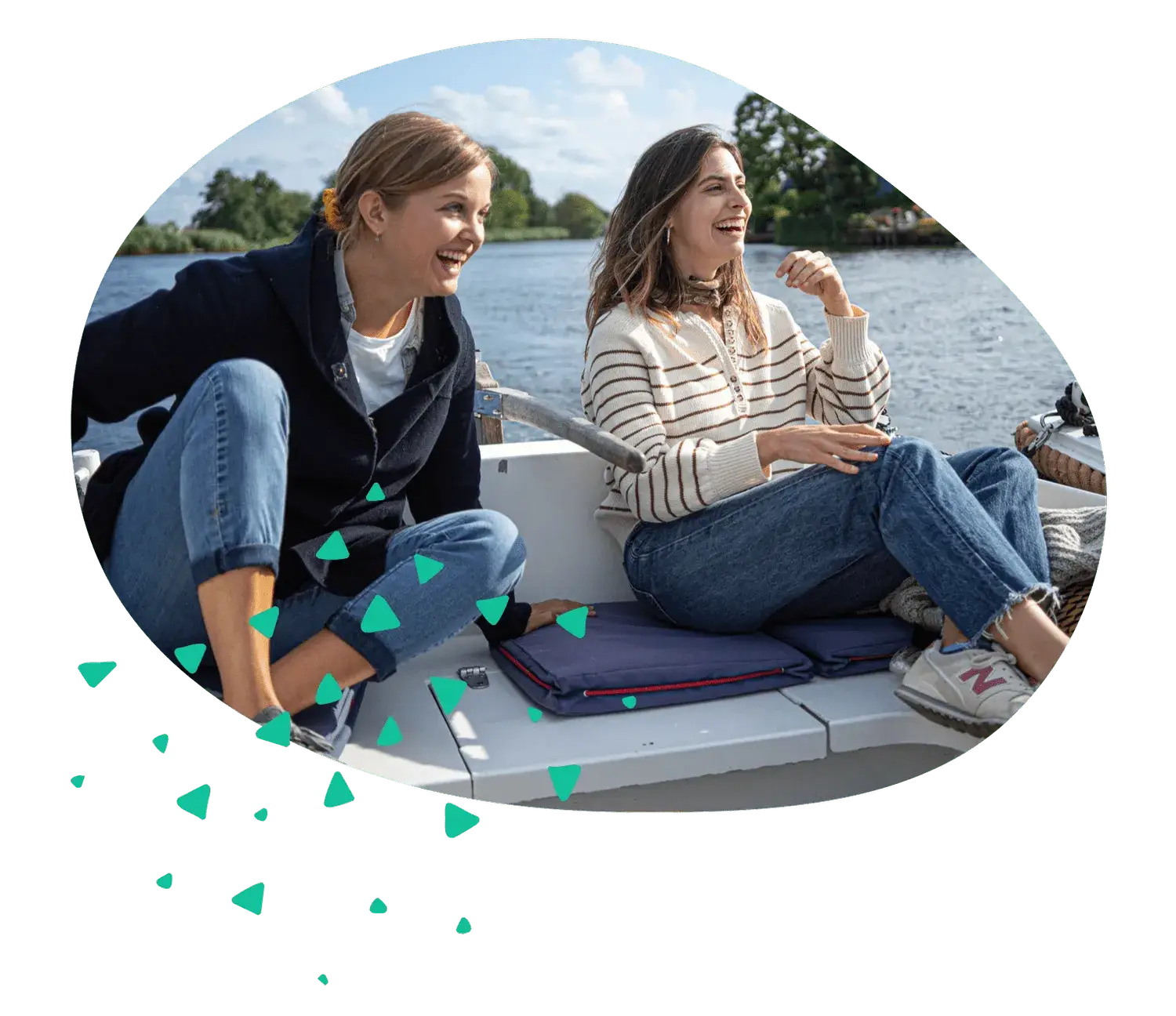 Two women laughing on the cushioned seats of a small open boat on the water