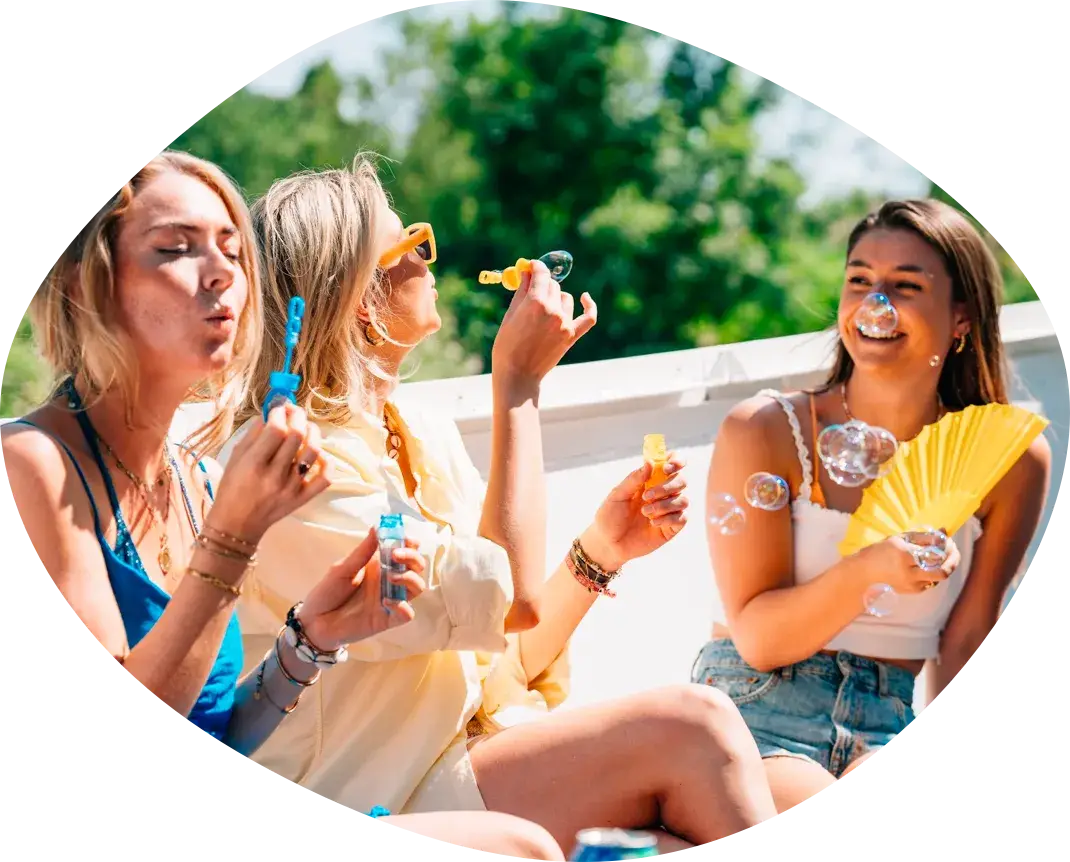 Three friends on board blowing soap bubbles in the sun