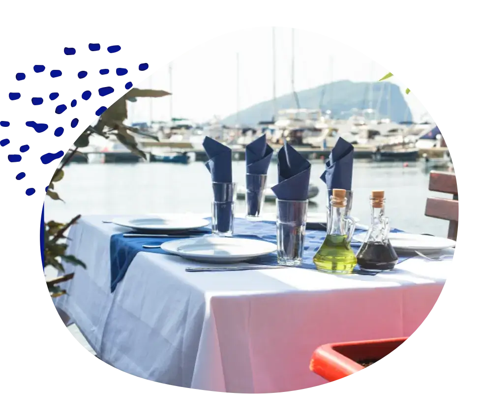 A table laid for four on a terrace by a marina full of boats