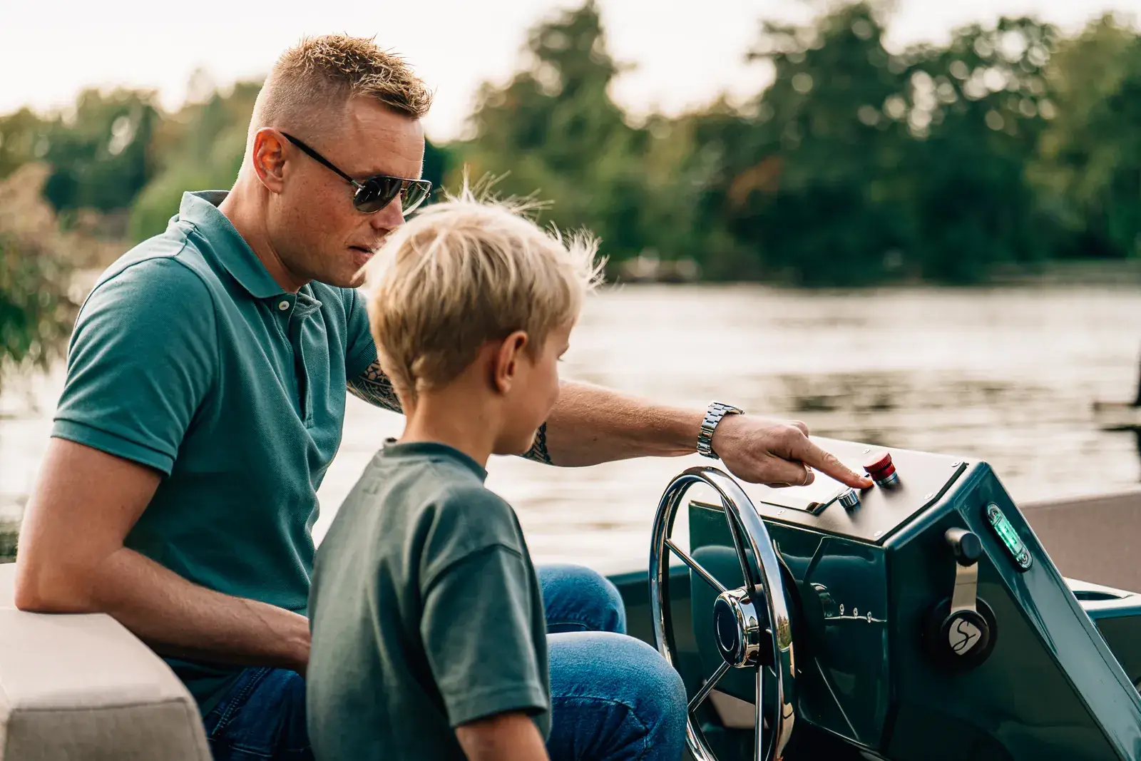 Un père et son fils à la barre d'un bateau électrique sur un lac