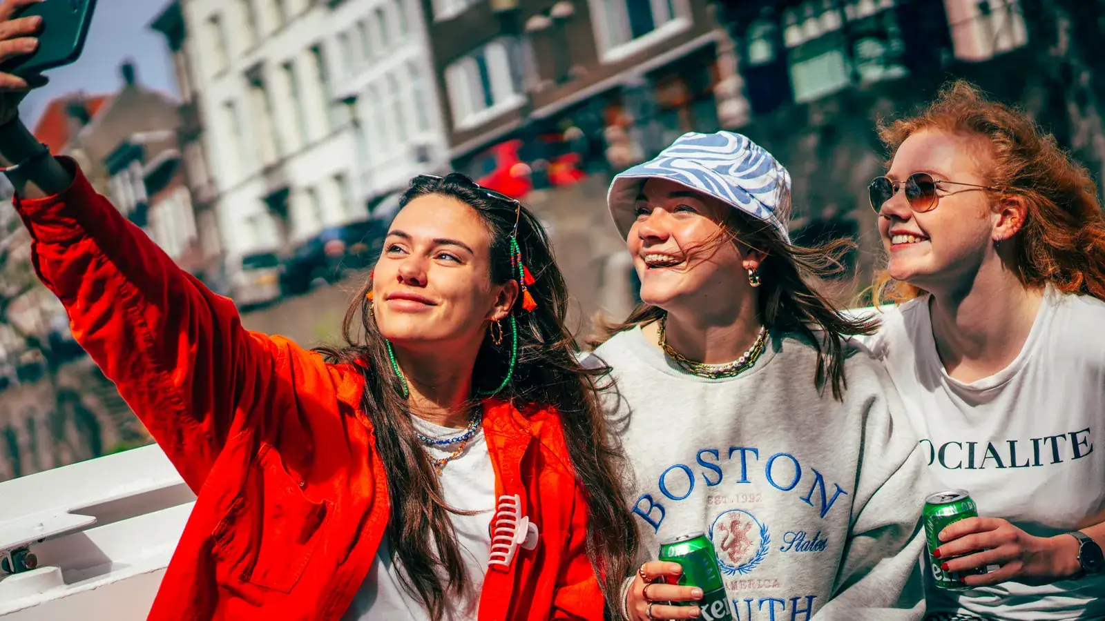 Trois amies prennent un selfie à bord d'un bateau sur un canal, deux d'entre elles tiennent une canette