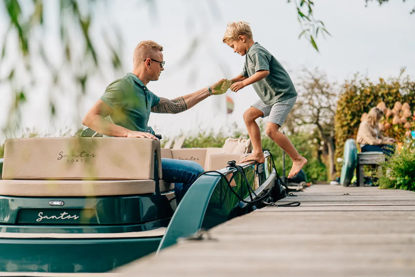 Een man die zijn hand uitsteekt naar een jongen die aan boord stapt van een elektrische boot