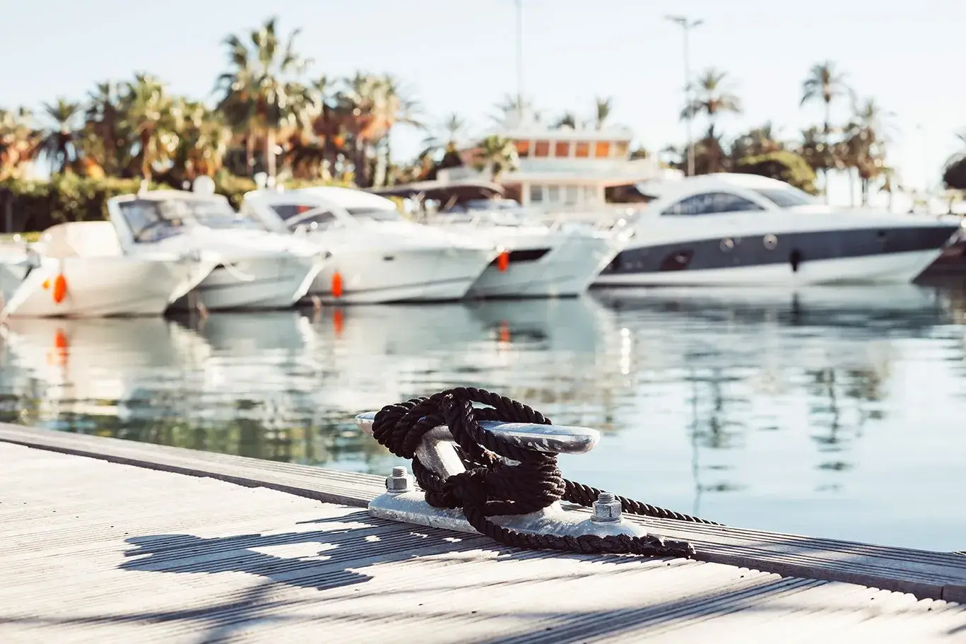 Motor yachts moored along a pontoon, with a mooring cleat in the foreground