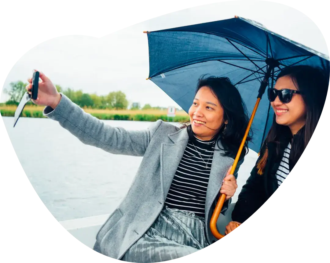 Two people taking a photograph of themselves under an umbrella in the rain