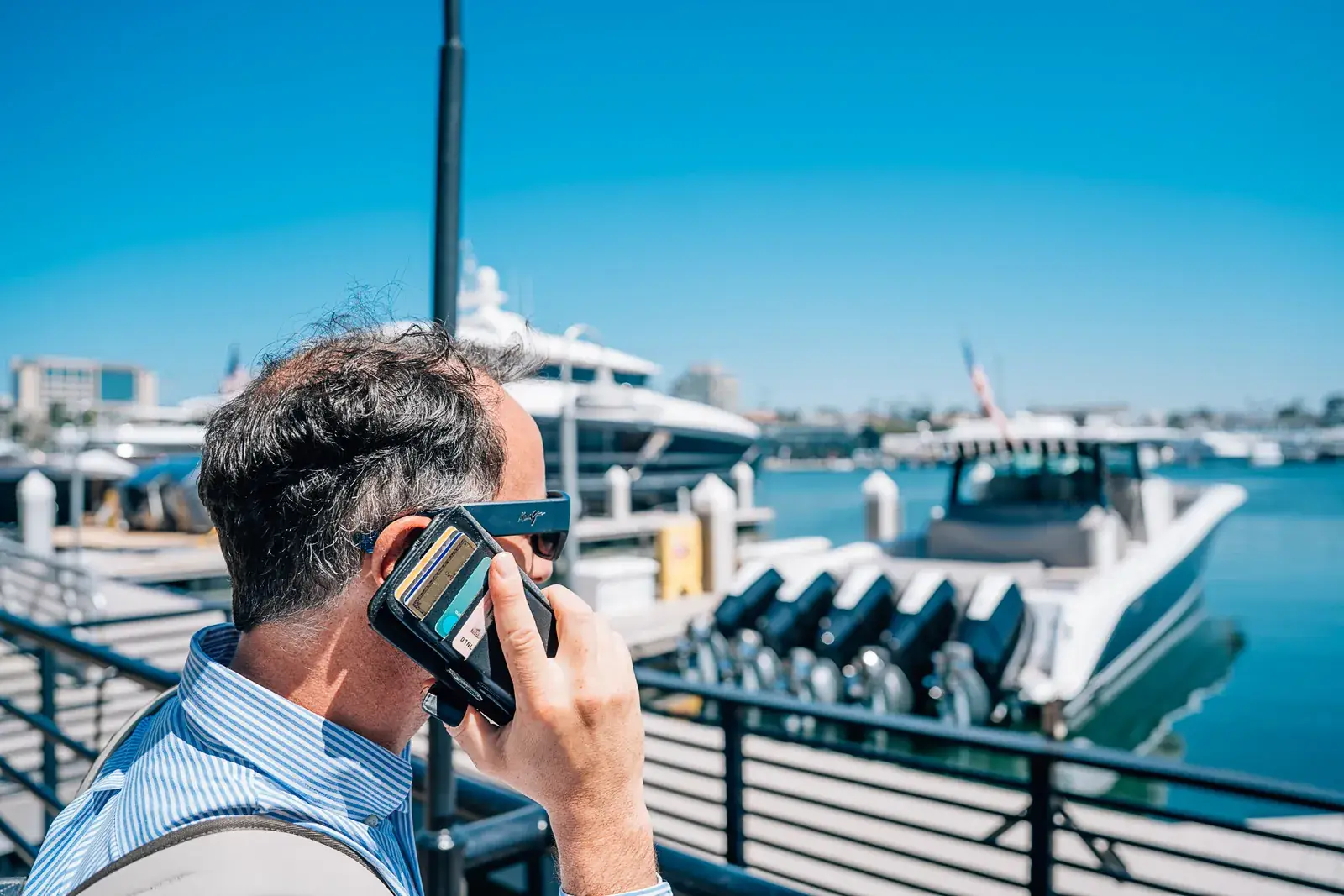 Ein Mann am Telefon an der Reling über einem Yachthafen voller Motoryachten
