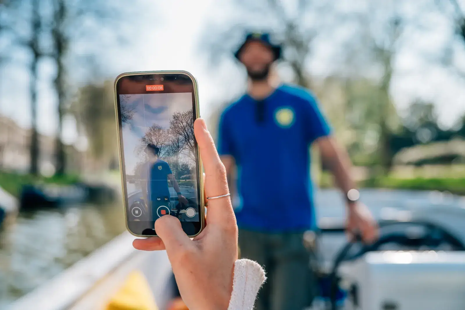 A phone photographs a crew member on a canal boat, for the pictures on the website