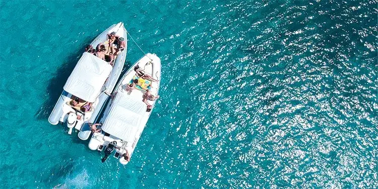 Two rental boats with passengers on board, seen from above on clear water