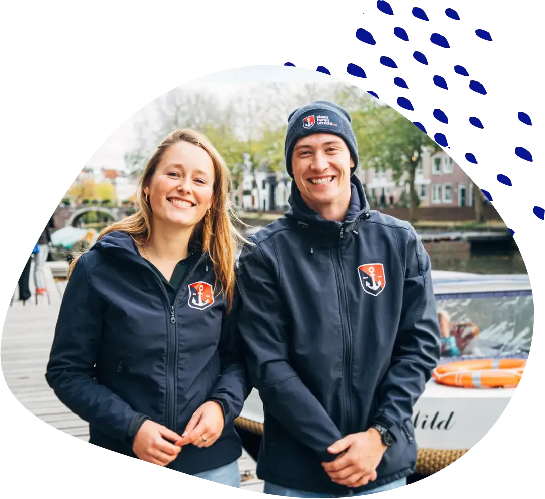 Two members of staff in branded jackets standing by the water