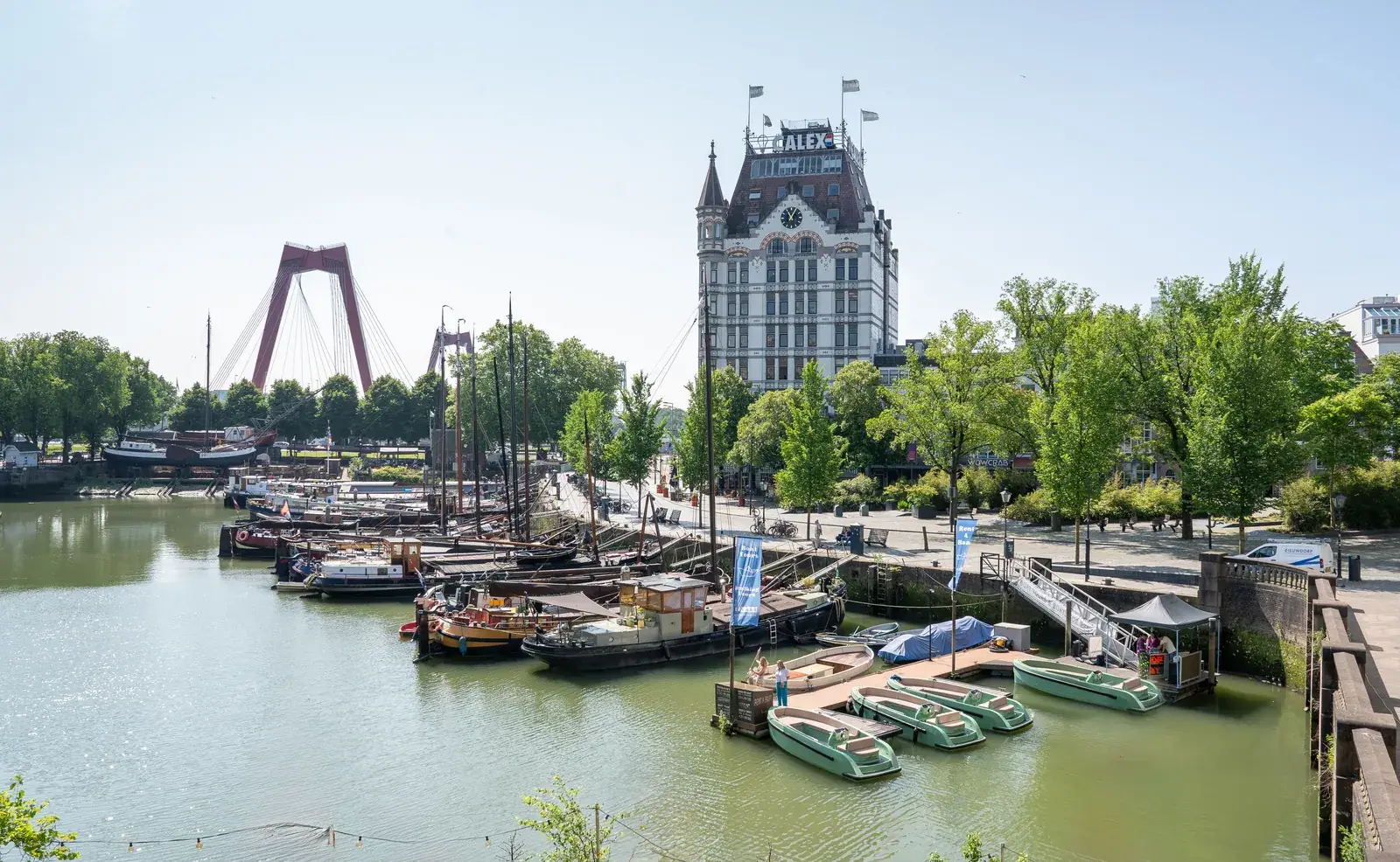 Een rij groene huursloepen in de Oude Haven van Rotterdam, met het Witte Huis erachter
