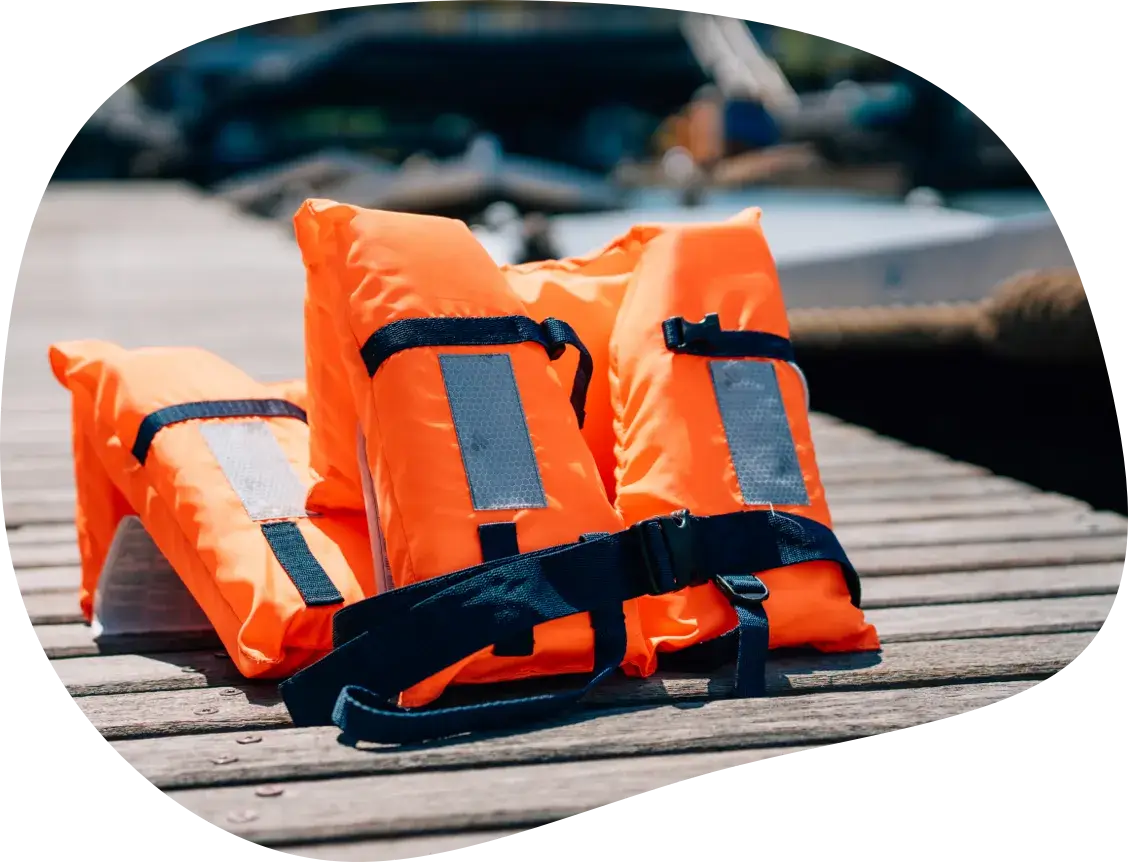 Three life jackets laid out on a wooden dock