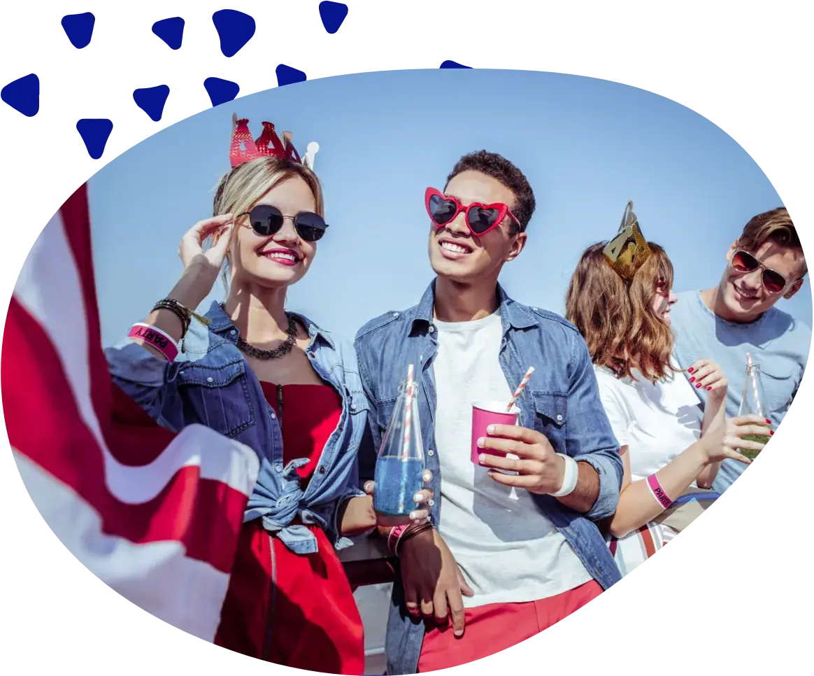 Four friends with drinks, sunglasses and party crowns, a red-and-white striped flag in the foreground