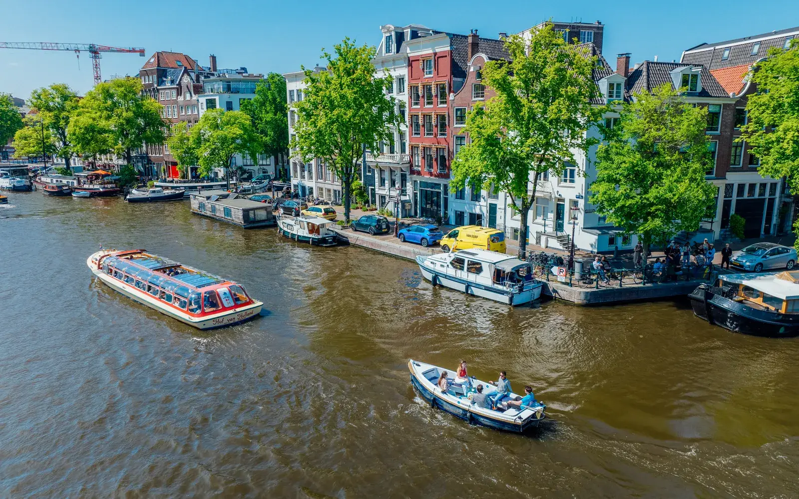 Een huursloep en een rondvaartboot met glazen dak op een Amsterdamse gracht, van bovenaf