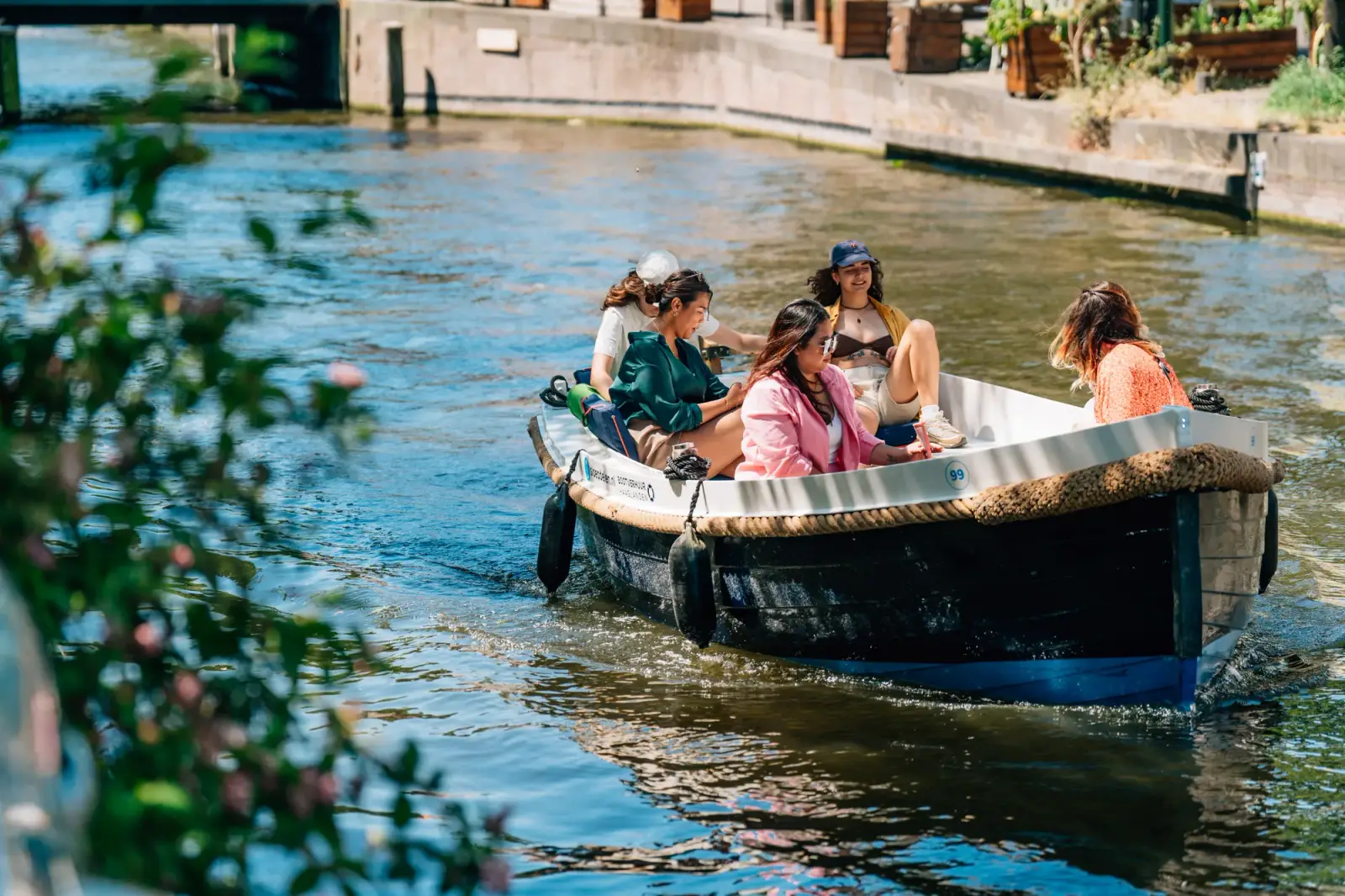 Friends out on a rental sloop on a tree-lined canal in The Hague