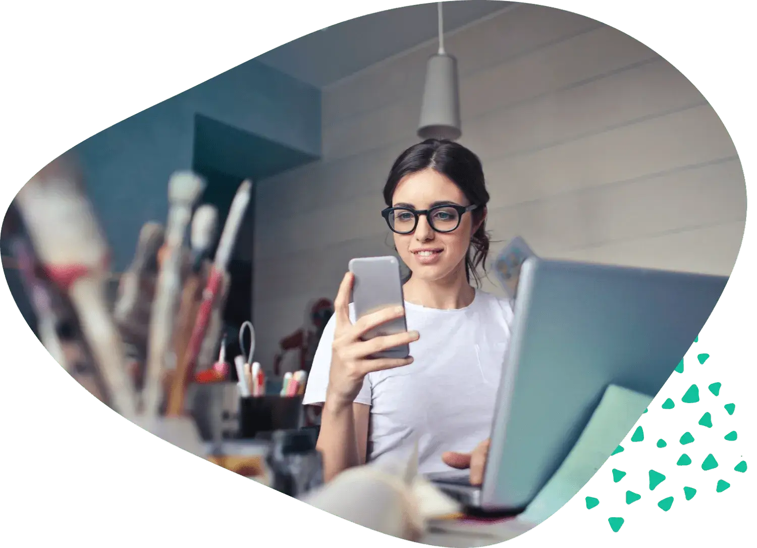A woman at a desk taking a photograph with her phone