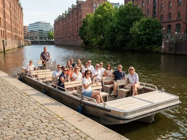 Ein offenes Ausflugsboot voller Gäste auf einem Fluss in der Stadt, vor alten Backsteinspeichern
