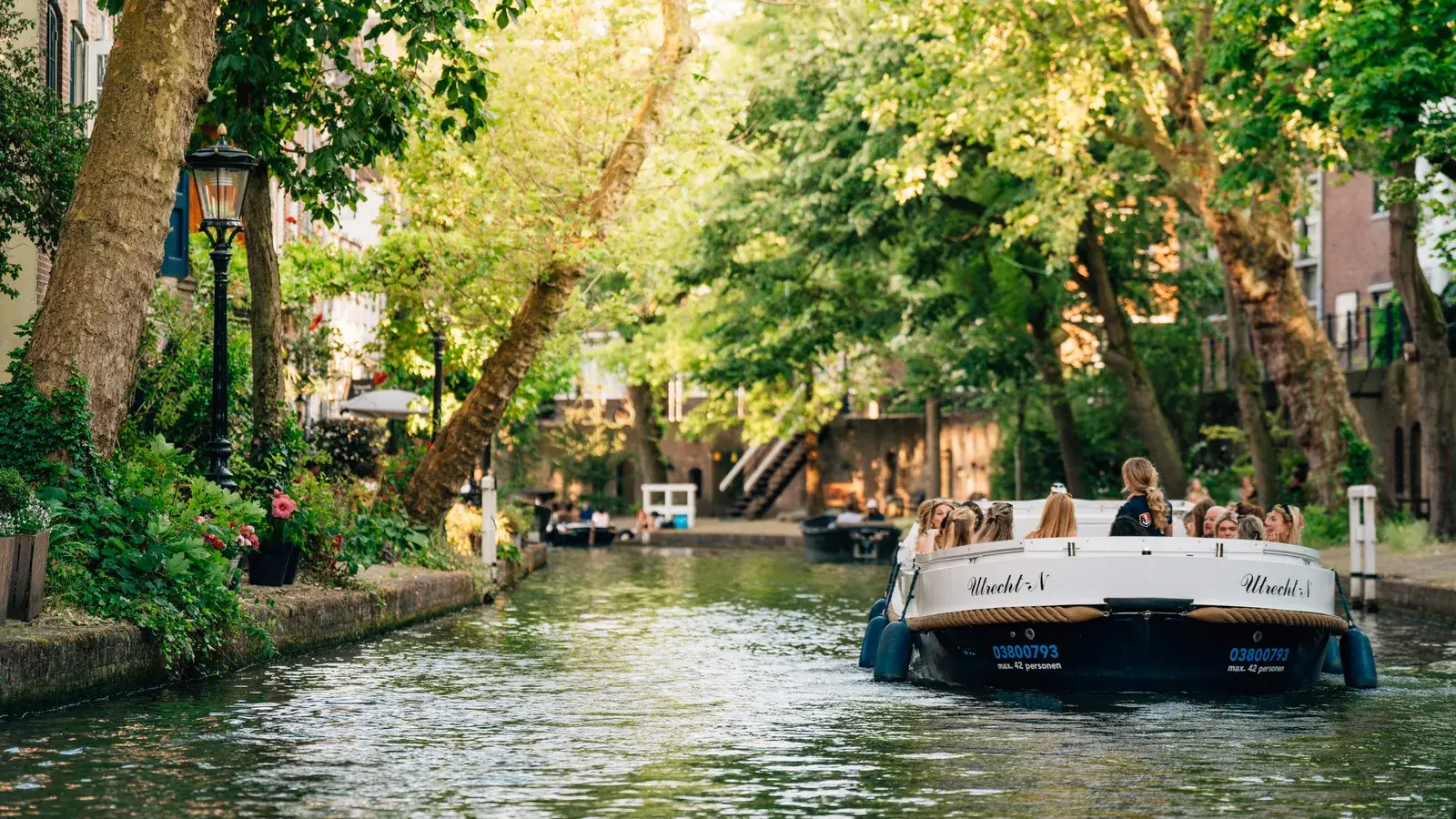 Un bateau-promenade plein de clients sur un canal vert sous les arbres